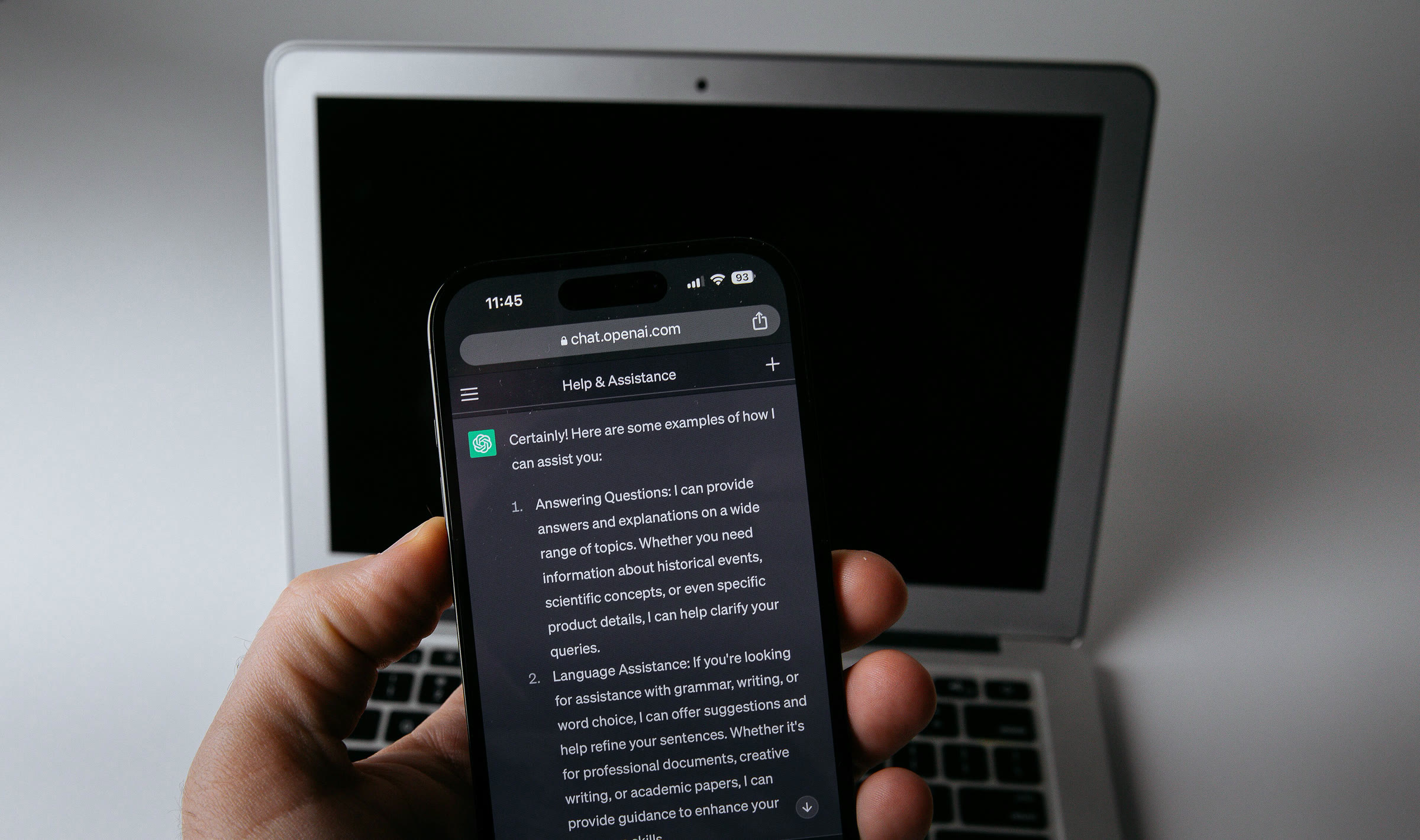Dizüstü bilgisayar önünde ChatGPT uygulaması açık telefon